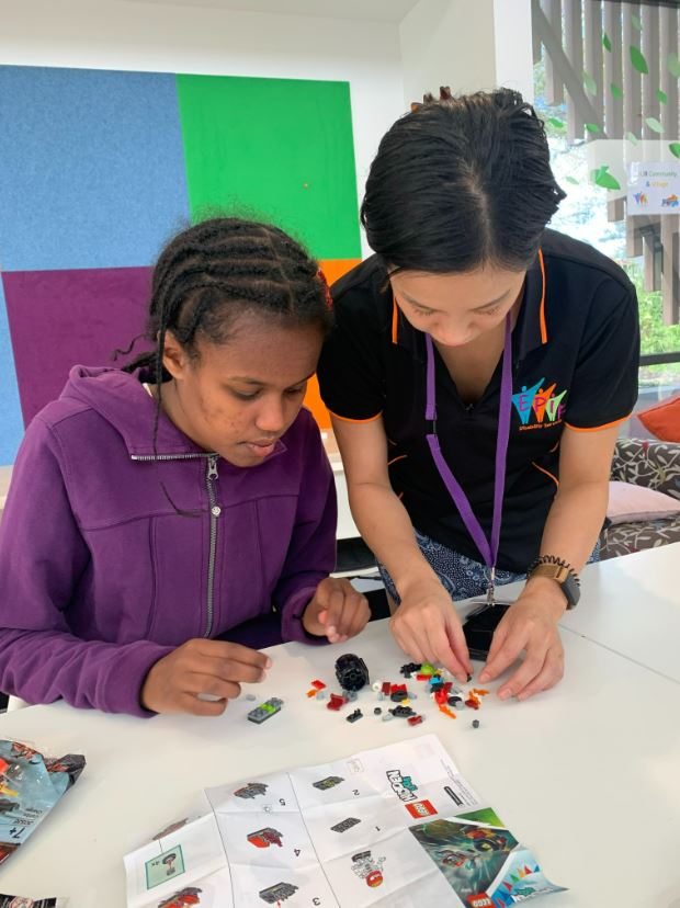 Support worker helping participant make a Lego figurine together at the table